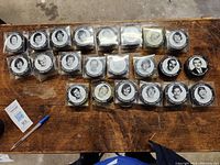 Top-down view of 22 hockey pucks featuring Team Canada 1972 player photos in clear plastic cases arranged on a table.