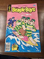 Front cover of The Beagle Boys comic book showing the Beagle Boys characters surfing with a pink background and 35 cent price tag.