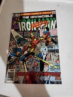 Front cover of the comic showing Iron Man in action with a colorful busy city scene. Includes title and issue information plus presence of a red dot on cover.