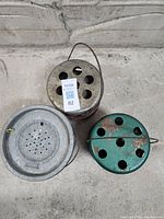 Top view of the three items including minnow pail and two Coleman heaters showing rust and ventilation holes.