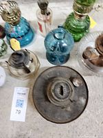 Top down photo showing the lamps arranged close together, showing diversity of glass colors, shapes, and the metal lamp base at center.