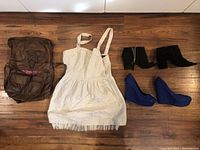 Top down view of dress, handbag and two pairs of shoes on hardwood floor