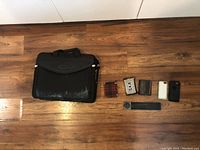 Photo of entire lot showing black laptop bag, three wallets, two phone cases, and two small incense catchers arranged on floor.