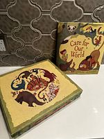 Image showing the Care for Our World book and the matching animal puzzle box with various illustrated animals on the front, displayed against a decorative tile background.