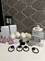 Assorted hardware pieces laid out on countertop, showing flower-shaped knobs, white wooden finials, black metal ring pulls, and packaged Ikea Energyda knobs.