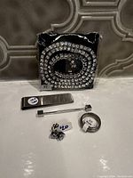 Photo showing the entire men's jewellery set including rhinestone necklace, money clip, tie tack, stud earrings, and ring arranged on a surface.