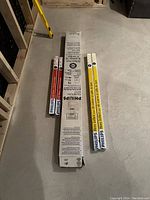 Photo showing six Philips bulbs of different sizes and uses, all new in original packaging arranged on floor.