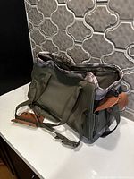 Soft sided cat carrier in green fabric with patterned interior lining and carrying straps shown from one side