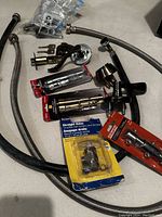 Photo showing various door handles including lever style handles, flexible braided hoses, lock cylinder with keys, and valves packaged and unpackaged.