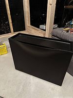 Front view of the black plastic floating shoe rack showing its curved design and slim profile.