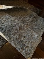 Gray fuzzy rug showing soft plush texture and slight wear.