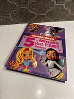 Front cover showing Nickelodeon 5-Minute Girl Power Stories book with illustrations of female characters and unicorn on purple background.
