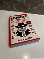 Front cover of the Murdle Volume 1 mystery puzzle book by G.T. Karber showing stylized detective artwork and title.