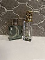 Two Berger lamps side by side on countertop, showing differing colors, shapes, and decorative tops.