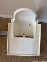Overhead view of the white plastic baby high chair seat with attached tray showing cutouts for safety straps.