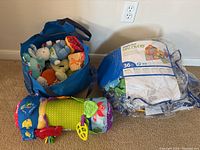 Two reusable bags, one full of assorted soft baby toys including stuffed animals and rattles, and the other containing a sealed 36-piece Discovery building set.