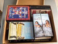 Top view of box containing miscellaneous DVDs including The Break-Up and Sunshine Cleaning.