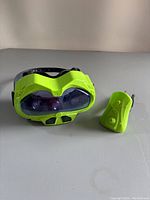 Front and side view of bright green Fotorama Alien Vision goggles with clear dark blue lenses, showing sci-fi design details and black strap