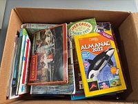 Box of assorted children's books including partial titles, colorful covers, educational and storybooks.