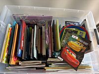 Plastic container with approximately 50 assorted children's books viewed from the top showing many book spines and covers.