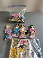 Set of four wooden magnetic dolls with names Sarah, Mia, Eva, Hannah and bags of magnetic clothing and elastic bands