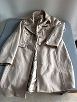 Khaki beige colored women's peacoat laid flat showing front side, button closures, lapel collar, chest pockets, and belted waist detail.