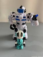 Front view of large white and blue robot and small turquoise robot on a flat surface