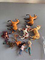 Overhead view of seven toys including three horses and four dolls with accessories