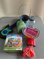 Overview of various toys including guitar, puzzles, basket, cloth item, jar, and plastic grill toy