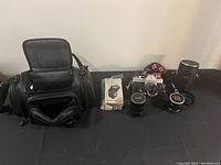 Full lot with camera bag, boxed accessory, camera with lens, additional lens, flash unit, and camera strap.