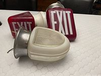 Three items displayed: two red EXIT sign housings and one white Art Deco glass ceiling light