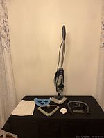 Hoover 2 in 1 steam and scrub mop upright with multiple accessories laid out including cleaning pads, scrubber frame, hose and cloth.