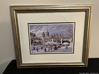 Photo showing the entire framed print titled 'Winterlude on the Canal' by Inge Claussen, with visible cityscape and ice skaters in winter scene.