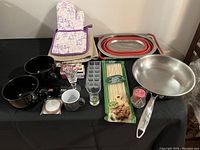 Photo of various kitchen items including mugs, glasses, frying pan, drying mats, oven mitt, strainer, bamboo skewers.