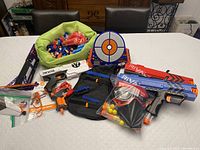 Overview of Nerf Rival blasters, darts, target, vest, and accessories displayed on table.