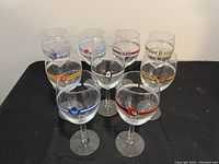Photo showing nine NHL wine glasses with logos displaying various teams on a black surface.