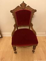 Front view of red velvet antique chair with carved wooden frame.