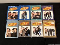 Nine DVD cases arranged in two rows showing all seasons 1 through 9 of Seinfeld series.