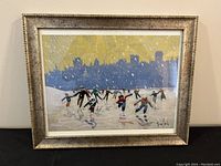 Framed print titled 'Skating on the Canal' showing skaters on a frozen canal with a city silhouette under a yellow sky, in a gold textured frame.