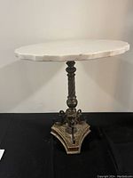 Full side view of the small marble top table with ornate metal base, showing the height and design details.