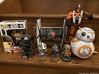 Photo of Star Wars collectible toys including a boxed Funko Pop! Vinyl figure, two black and white mini helmets, droid and pilot action figures.