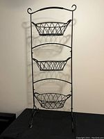 Full view of the three-tier wrought iron fruit and vegetable stand with hanging baskets.