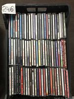 Top view of the plastic bin filled with used music CDs with visible spines showing album and artist names including Celtic favorites and Tony Bennett.