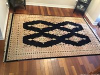 Full view of hand knotted rug showing pattern and overall condition laid on hardwood floor.