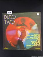 Front cover of Disco Two vintage LP record, showing a dancing woman with colorful disco lights and track titles including Blockbuster, Dancing On A Saturday Night, Superstition, and more.
