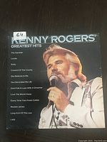 Front cover of Kenny Rogers Greatest Hits LP showing Kenny Rogers with microphone, listing songs vertically on left side.