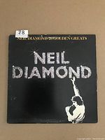 Front cover of the Neil Diamond 20 Golden Greats LP record showing title and artist name in silver glitter style text with image of Neil Diamond singing with a microphone.