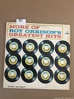 Front cover of 'More of Roy Orbison's Greatest Hits' album showing illustrated 45rpm records with titles.
