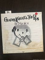 Front cover of Gladys Knight & The Pips LP titled 'Imagination', showing band members posing with picture frames on white background.