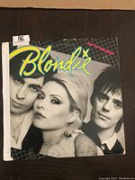 Front cover of Blondie LP record with three band members in black and white, neon blue and yellow band title text.
